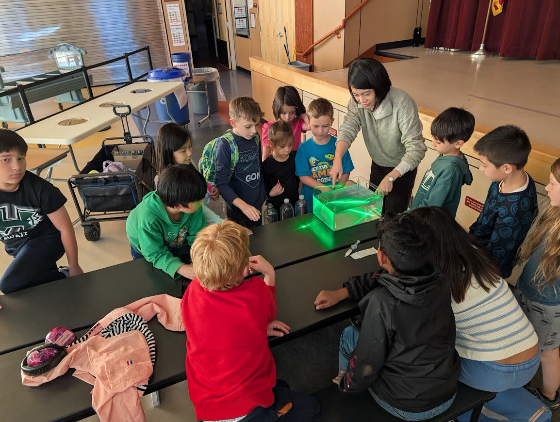 Dr. Tao showing a group of students green laser light traveling through a water tank